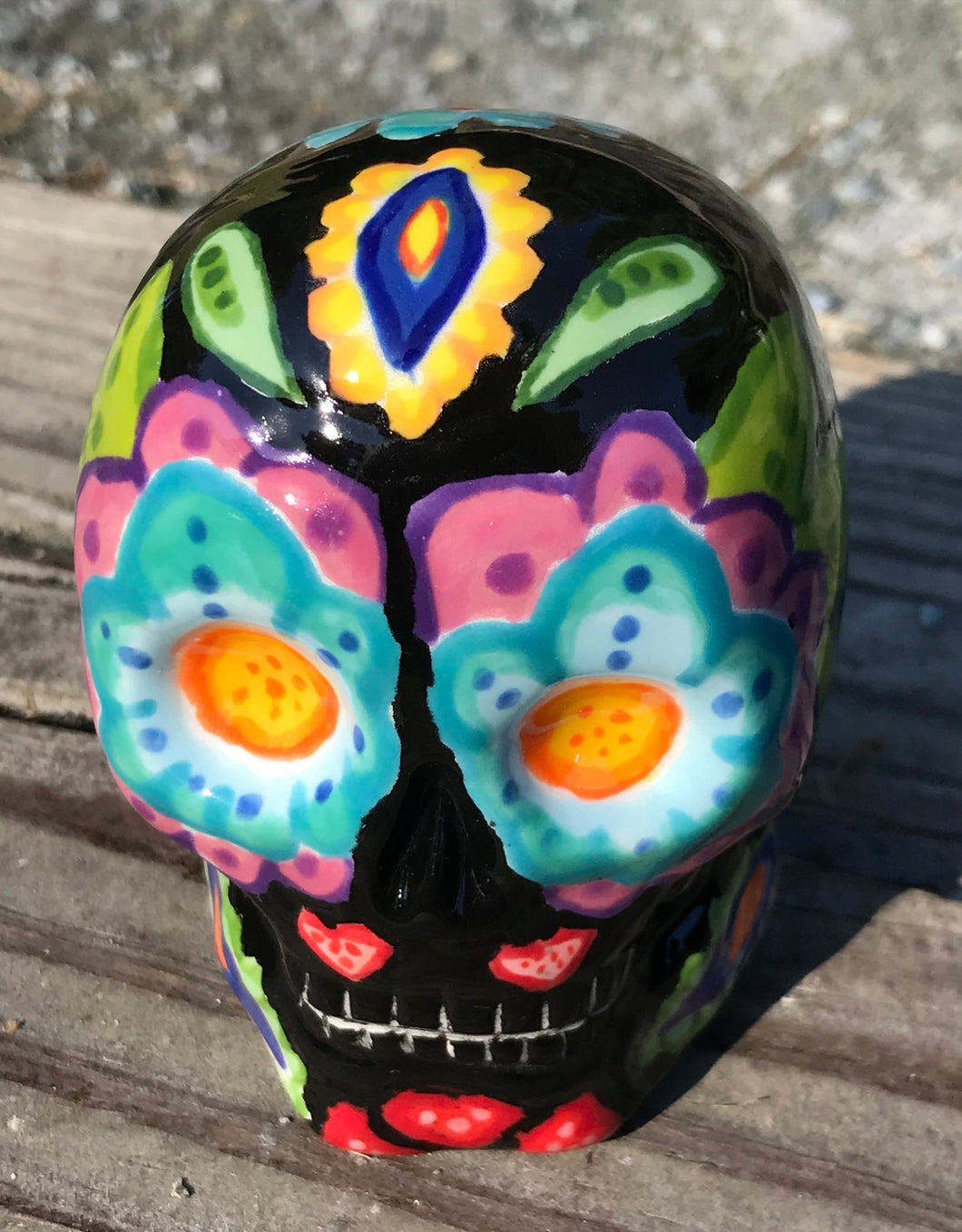 This black ceramic sugar skull, inspired by nature, is adorned with hand-painted floral motifs, hearts, leaves and colorful accents. Its vibrant style and intricate details create a stunning Dia De Los Muertos calavera. Perfect for creating ofrendas to celebrate the Day of the Dead. Measurements: H 2 3/4” x W 2” x D 2”