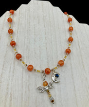 Load image into Gallery viewer, This bright orange, adjustable, choker-style necklace is adorned with beaded glass and a striking crescent moon charm and dragonfly pendant. Accessorize with matching dragonfly earrings for an eye-catching, complementary look that captures the warmth of summer. Perfect for any outfit, its vibrant colors will make a statement and complete any look.  Measurements: Necklace is 16 1/2”adjustable up to 19&quot; 

