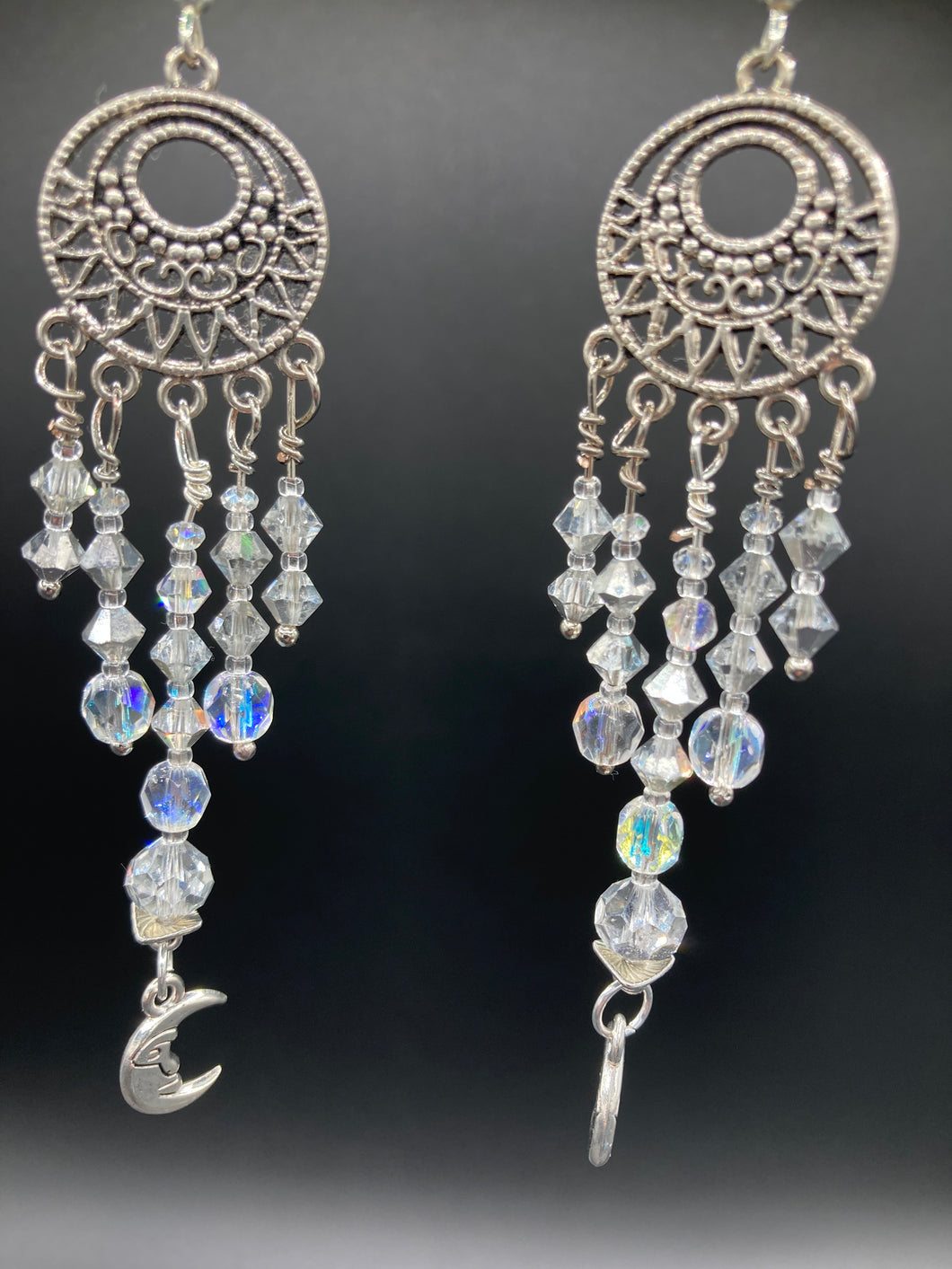 Crafted with five strands of stunning clear iridescent glass beads and dangling crescent moons, these large chandelier style earrings will add a celestial touch to any outfit.  Measurements: 4” in length
