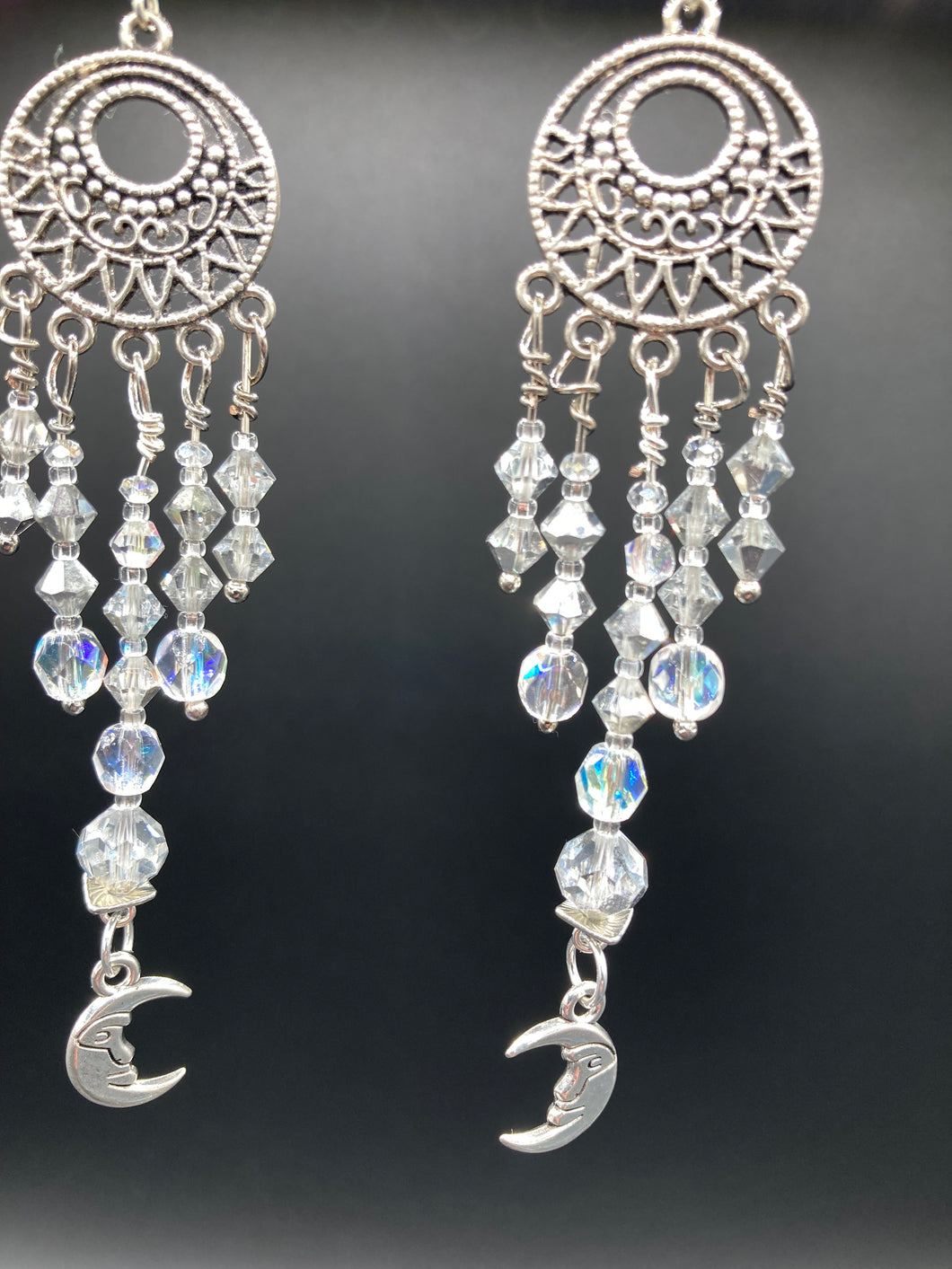 Whimsical Celestial Smiling Crescent Moons Large Chandelier Earrings. Five strands of beautiful clear iridescent glass beads and dangling smiling crescent moon charms. This is perfect for any outfit and will surely stand out. Measurements:  4” in length. Witchy, Whimsical, Goth, Luna Lovers, Crescent Smiling Moons