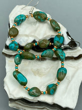 Load image into Gallery viewer, Our Blue-Green Magnesite Stone Beaded Hoop Earrings provide a nature-inspired look that is perfect for any boho-chic style. These earrings feature natural magnesite stone beads with small beads of turquoise and gold glass for subtle accent. Show off your bohemian look with these eye-catching hoops. Measurements: 2&quot; length 
