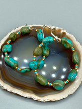 Load image into Gallery viewer, Our Blue-Green Magnesite Stone Beaded Hoop Earrings provide a nature-inspired look that is perfect for any boho-chic style. These earrings feature natural magnesite stone beads with small beads of turquoise and gold glass for subtle accent. Show off your bohemian look with these eye-catching hoops. Measurements: 2&quot; length 
