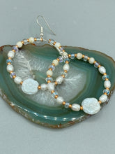 Load image into Gallery viewer, These white floral glass beaded hoop earrings bring a bohemian, shabby-chic, and nature-inspired vibe to any look. Crafted with small iridescent, gold, and white glass beads, they are the perfect accessory for any fashionista who loves beach vibes, summer elements, and chic boho styles. Measurements: 2 1/4" length
