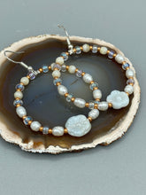 Load image into Gallery viewer, These white floral glass beaded hoop earrings bring a bohemian, shabby-chic, and nature-inspired vibe to any look. Crafted with small iridescent, gold, and white glass beads, they are the perfect accessory for any fashionista who loves beach vibes, summer elements, and chic boho styles. Measurements: 2 1/4" length
