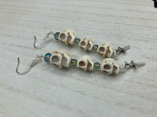 Load image into Gallery viewer, For The Dark Souls Three Howlite Skull Beads Light Blue Iridescent Glass Bead Earrings Dangling Silver Plated Cross Give These Earrings Movement. Chingona, Cabrona, Latina Chicana, Goth, Vampire Goth, Dark Witchy Style. You can dress these up or down, it will definitely give your outfit a unique look.  Measurements: 3 ” in length
