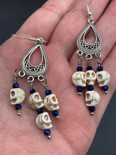 Stunning Cascade of Tiny Howlite Skull Dark Purple Glass Bead Chandelier Earrings. Chicana Chingona Chola Style Jewelry. Beautiful elegant set of teardrop earrings has an eerie beautiful vibe. Tiny dangling howlite skull beads. You can dress these up or down, it will definitely give your outfit a unique look. Versatile looks from Witchy, Goth, Dia De Los Muertos, Vampire Goth.  Measurements: 2” in length