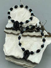 Load image into Gallery viewer, This sophisticated pair of earrings features a black glass fish bead, complemented by small iridescent and dark gray color glass beads, with eye and fin details. Measurements: 2” in length  
