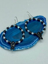 Load image into Gallery viewer, This sophisticated pair of earrings features a black glass fish bead, complemented by small iridescent and dark gray color glass beads, with eye and fin details. Measurements: 2” in length  
