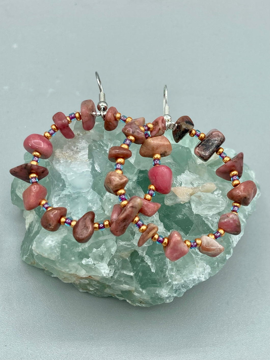 These Rhodonite Stone Chip Beaded Hoop Earrings feature natural rhodonite stones and light purple and gold glass beads for a shabby chic, boho chic, and nature-inspired bohemian look. Measurements: 1