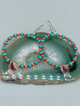 Load image into Gallery viewer, This eye-catching set of earrings features intricately detailed koi fish glass beads, accompanied by smaller teal, red, and gold-hued glass beads. With their bold and vibrant colors, they make a striking statement.  Measurements: 2 1/4” in length   
