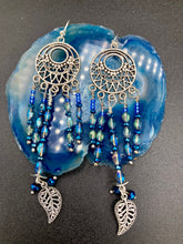 Load image into Gallery viewer, These intricate moroccan blue Inspired large chandelier earrings boast five strands of blue and iridescent glass beads of various hues, including silver and gold. Additionally, two small dark blue glass beads with a silver leaf add a touch of dimension and motion. The perfect addition to any Fairy Princess or whimsical aesthetic.  Measurements: 4” in length
