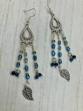 Load image into Gallery viewer, Blue Moroccan Inspired Large Chandelier Earrings. Three strands of beautiful blue and iridescent glass beads with intricate silver plated leaf charms create a lot of movement. Versatile, perfect for whimsical fairy princes, good witch, hippie nature lovers looks. These earring will compliment any look.  Measurements: 3 1/2” in length
