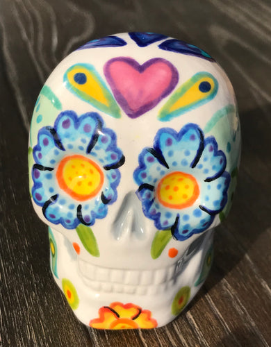 This stunning Mini Dia de Los Muertos Calavera is a one-of-a-kind hand-painted ceramic sugar skull, with an aquatic-inspired color palette. The unique flower on the back of the skull is painted to look like the head of a jellyfish. Display this beautiful piece of art and enjoy the elegance and beauty of its delicate dance.  Measurements: H 2 3/4” x W 2” x D 2”