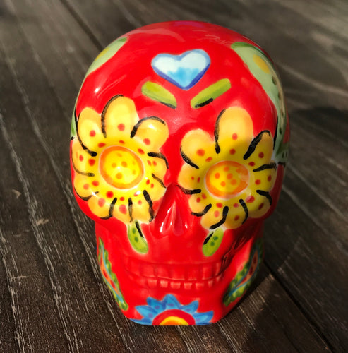 This ceramic skull statuette is a stunning piece of art inspired by nature. Its vibrant red hue is decorated with multi-color floral motifs, hearts, leaves and colorful accents, creating a beautiful piece of hand-painted, Day of the Dead-themed art. Measurements: H 2 3/4” x W 2” x D 2”