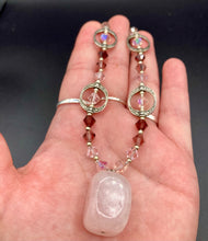 Load image into Gallery viewer, This exquisite necklace features a soft pink Rose Quartz pendant with multi-colored glass beads that transition from iridescent pink, to light purple and darker shades of purple. The sequence of beads complements the Rose Quartz pendant&#39;s delicate hue, and is accompanied with a set of subtly-styled matching earrings for a complete look.  Measurements:   Necklace is 16 1/2”
