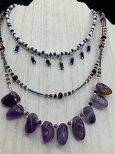 Load image into Gallery viewer, The Genuine Amethyst Natural Gemstone Adjustable Chocker Style Glass Beaded Necklace features vibrant violet and white tones. Its unique draped beading creates a beautiful style with a series of short strands of glass beads for movement and a longer strand with a multitude of amethyst nugget beads. The collar necklace hangs gracefully along the neck and chest, making it a dream come true for violet lovers.  Measurements:  Necklace is 15” in length adjustable to 18&quot; in length
