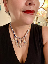 Load image into Gallery viewer, Howlite Skull Beads And Smiling Crescent Moon Charms Choker Style Glass Beaded Necklace. Two beaded stands that are primarily white and added purple glass beads that have hues of blue and gold. I wanted to incorporate dark and white glass bead colors to create a simple contrast. Large amount of dangling skulls and their smiling crescent moons add a lot of movement. Necklace is 16”adjustable up to 18" in length - hanging howlite skull with crescent moons are 2” Height
