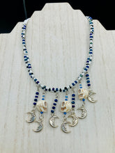 Load image into Gallery viewer, Howlite Skull Beads And Smiling Crescent Moon Charms Choker Style Glass Beaded Necklace. Two beaded stands that are primarily white and added purple glass beads that have hues of blue and gold. I wanted to incorporate dark and white glass bead colors to create a simple contrast. Large amount of dangling skulls and their smiling crescent moons add a lot of movement. Necklace is 16”adjustable up to 18" in length - hanging howlite skull with crescent moons are 2” Height
