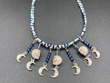 Load image into Gallery viewer, Howlite Skull Beads And Smiling Crescent Moon Charms Choker Style Glass Beaded Necklace. Two beaded stands that are primarily white and added purple glass beads that have hues of blue and gold. I wanted to incorporate dark and white glass bead colors to create a simple contrast. Large amount of dangling skulls and their smiling crescent moons add a lot of movement. Necklace is 16”adjustable up to 18" in length - hanging howlite skull with crescent moons are 2” Height

