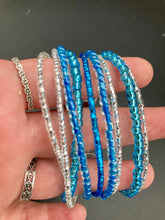 Load image into Gallery viewer, This bracelet is a chic, minimalistic design with nine beaded strands that feature various blue and silver glass beads. It measures 7 1/2&quot; in length and has been crafted with inspiration from the ocean blue waves.
