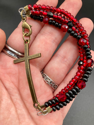For Positivity and Faith, Shimmery Red And Black Glass Beaded Bracelet With Curved Horizontal Brass Cross. This bracelet has a large brass cross that is slightly curved to be comfortably worm around your wrist.  I created four different black and red glass beads strands. Measurements: 7 1/2