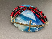 Load image into Gallery viewer, For Positivity and Faith, Shimmery Red And Black Glass Beaded Bracelet With Curved Horizontal Brass Cross. This bracelet has a large brass cross that is slightly curved to be comfortably worm around your wrist.  I created four different black and red glass beads strands. Measurements: 7 1/2&quot; in length, brass cross measures 2&quot; in length. 
