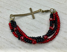 Load image into Gallery viewer, For Positivity and Faith, Shimmery Red And Black Glass Beaded Bracelet With Curved Horizontal Brass Cross. This bracelet has a large brass cross that is slightly curved to be comfortably worm around your wrist.  I created four different black and red glass beads strands. Measurements: 7 1/2&quot; in length, brass cross measures 2&quot; in length. 
