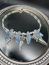 Load image into Gallery viewer, This elegant and dark necklace features shimmering light silver and gray glass beads of varying sizes and shapes for texture and dimension. The necklace is finished with blue luster crystal stone nuggets and nickel-free dagger pendants, creating a beautiful draping effect. Measurements:   Necklace is 17”adjustable up to 19&quot; 

