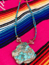 Load image into Gallery viewer, This vibrant and striking double strand necklace features a combination of glass beads in blue and green shades of turquoise, gold and champagne. The two delicate strands are accented with a gold-tone flower-shaped bead, a howlite stone chip dyed in turquoise, and shimmery, cross-faceted champagne-colored glass beads to complete the dramatic look.  Measurements:   Necklace is 17” and can be adjusted up to 19"
