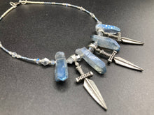 Load image into Gallery viewer, This elegant and dark necklace features shimmering light silver and gray glass beads of varying sizes and shapes for texture and dimension. The necklace is finished with blue luster crystal stone nuggets and nickel-free dagger pendants, creating a beautiful draping effect. Measurements:   Necklace is 17”adjustable up to 19&quot; 
