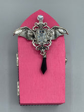 Load image into Gallery viewer, This unique handmade Pink Spooky Glam Wood Coffin Ring Box offers a statement piece for your witchy home decor. Its macabre collections boast a black and pink wood coffin with large shimmery bat embellishments and decorative black crystals around the exterior. Open up the box to find a bright turquoise mandala fabric and a tiny black crystal bat decoration for a truly eerie feel.
