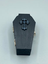 Load image into Gallery viewer, This unique vintage-inspired ring box is perfect for storing your jewelry and other special items. The wood coffin design is accented with a detailed black silver cross. The interior is lined with a skull fabric and a large dark red rose, adding a spooky yet elegant flair.
