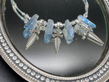 Load image into Gallery viewer, This elegant and dark necklace features shimmering light silver and gray glass beads of varying sizes and shapes for texture and dimension. The necklace is finished with blue luster crystal stone nuggets and nickel-free dagger pendants, creating a beautiful draping effect. Measurements:   Necklace is 17”adjustable up to 19&quot; 
