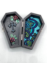 Load image into Gallery viewer, This vintage-inspired coffin ring box will make a spooky yet cute addition to any jewelry collection. The sleek black box has eye-catching black and gray embellishments, while the interior is beautifully decorated with a vivid turquoise blue fabric and a highly detailed black and silver cross with dark red roses. Function and style meet with this unique and stylish piece.
